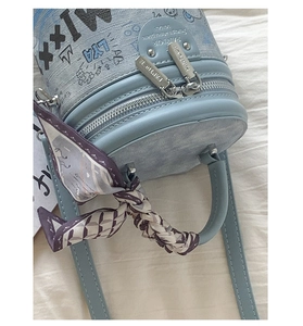 Dettaglio della borsa a secchiello azzurra con stampe graffiti e manico in foulard