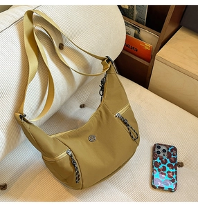 Détail d'un sac bandoulière croissant jaune moutarde avec poches zippées et logo M