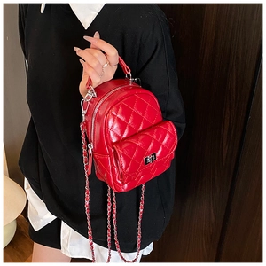 Close-up of red quilted mini backpack with glossy finish and silver chain strap