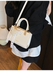 White minimalist crossbody bag with woven handle and pearl heart charm on model
