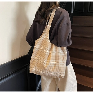 Detail of yellow checkered canvas tote bag with decorative white lace embroidery