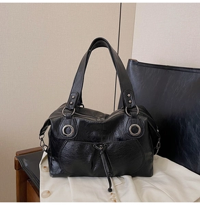 Detail of black faux leather tote with crinkled texture, silver rings and rivet accents
