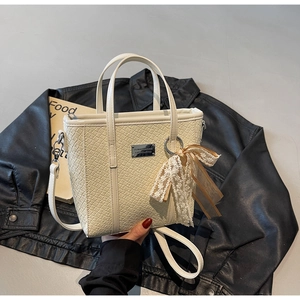 Dettaglio della borsa tote intrecciata panna con fiocco in pizzo e tracolla rimovibile