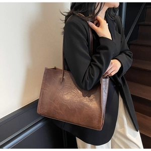 Detail of vintage brown tote bag showing textured leather material and shoulder strap
