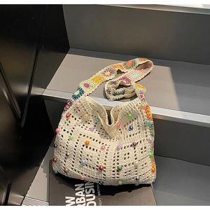 Detail der weißen Häkeltasche mit bunten Perlen und Blumen-Schultergurt auf Steinstufen