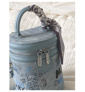 Dettaglio della borsa a secchiello azzurra con stampe graffiti e manico con foulard