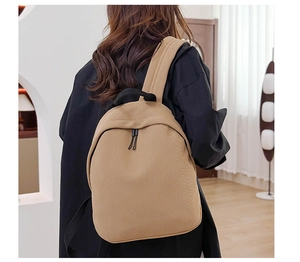 Close-up of khaki Oxford cloth backpack with handle and zipper on model back