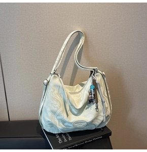 Detail of marble pattern tote bag with teddy bear pendant and designer logo patch