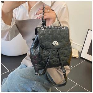 Detailed view of black star-quilted mini backpack with silver metal twist lock and chain strap