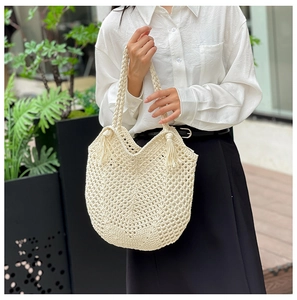 Détail du sac cabas au crochet beige avec texture en maille ajourée et pompons stylés