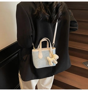 Détail du sac seau bleu clair avec motifs en relief et charmant pendentif peluche