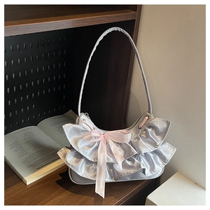 Detail of silver satin ruffled shoulder bag with soft pink silk ribbon bow accent