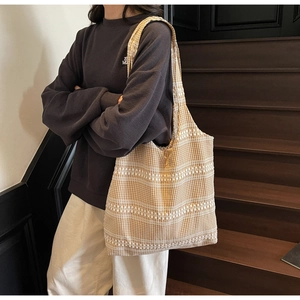 Detail of yellow checkered canvas tote bag with white geometric embroidery on shoulder strap