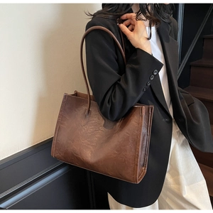 Side view of soft dark brown vintage PU leather tote bag worn by a model in a blazer