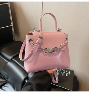 Detail of pink leather handbag with silver braided chain and metal twist lock