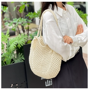 Détail du sac cabas en crochet tissé main blanc crème avec pompon élégant et bandoulière