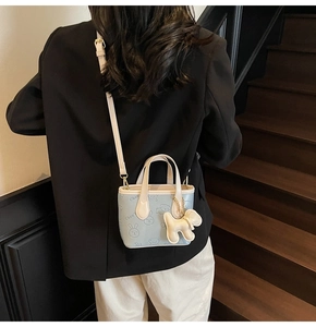 Détail du sac seau bleu clair avec silhouettes de dessins animés et pendentif peluche