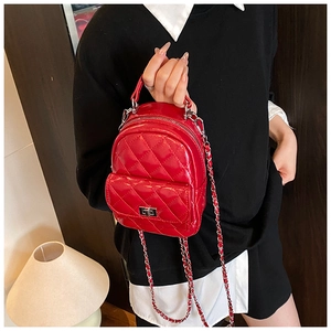 Detail of red quilted backpack with metallic silver lock and chain strap carried by hand