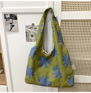 Detail of floral printed green nylon crescent bag hanging on a white cabinet handle