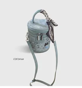 Dettaglio della borsa a secchiello azzurra con graffiti a cartoni e foulard in seta sul manico