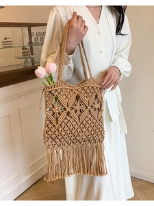 Handwoven straw tote bag with fringe tassels and intricate crochet patterns for beach vacation