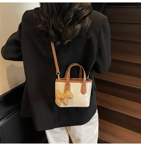 Détail d'un mini sac cabas avec imprimés chien et breloque en peluche sur escalier