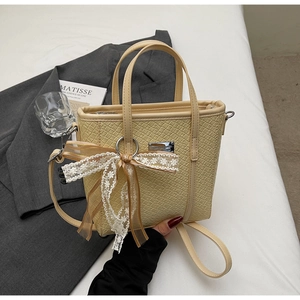 Dettaglio borsa a secchiello beige con fiocco in pizzo decorativo e placca in metallo elegante