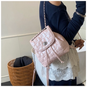 Detail of pink star-quilted mini bag with silver chain strap worn cross-body