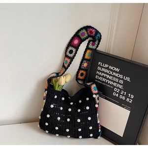 Detail der schwarzen Häkeltasche mit Perlen und floralem gestricktem Schultergurt