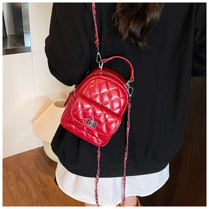 Detail of red quilted leather backpack with silver turn-lock and chain strap on model