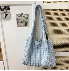 Detail of blue and white striped seersucker crescent bag with purple brand label