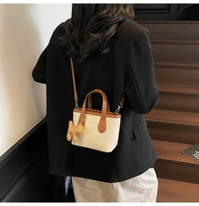 Détail du mini sac seau avec gaufrage ours 3D et breloque chiot sur l'épaule du mannequin