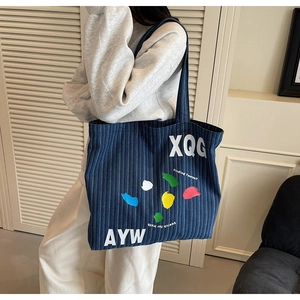 Detail of large denim tote bag featuring striped fabric and street style graphic print