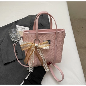Dettaglio della borsa a secchiello rosa con fiocco in pizzo e trama geometrica