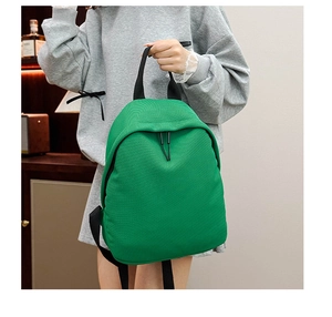 Close-up of green Oxford cloth backpack showing granular texture and black top handle