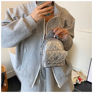 Detail of silver quilted mini backpack featuring chain straps and square turn-lock closure