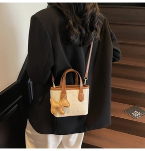 Vue détaillée du mini sac seau avec gaufrage ours et joli charm de chien marron
