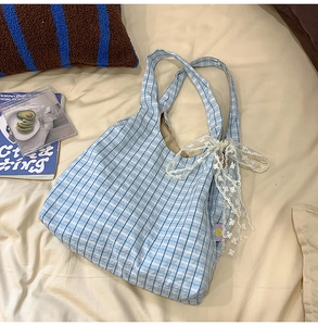 Detail of light blue gingham dumpling bag with decorative white lace bow on the side