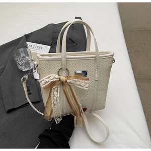 Dettaglio della borsa tote intrecciata crema con fiocco di pizzo e finiture in oro chiaro