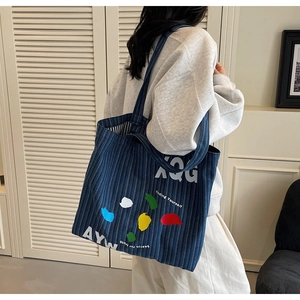 Detailed view of striped denim tote bag worn by a model against a clean white background