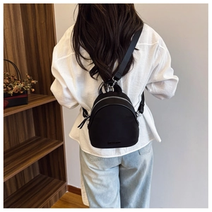 Detail of a black nylon mini shell backpack with silver zippers and wide fabric strap
