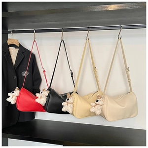 Collection of half-moon shoulder bags in red, black, yellow, and beige with plush bear charms