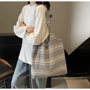 Detail of checkered canvas tote bag showing gingham pattern on model's shoulder