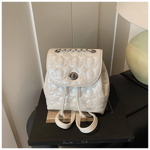 Close-up of cream white bucket bag featuring star quilting and metal chain strap