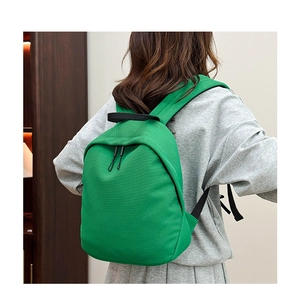 Detail of light green waffle textured backpack with black straps on female model