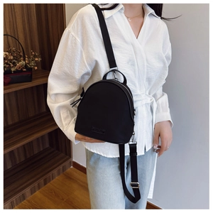 Detail of a black mini nylon backpack showing silver metal rings and adjustable straps