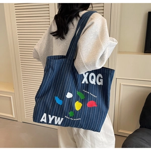 Close-up of durable striped denim tote bag with colorful artistic ink splash and text