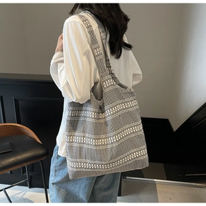 Detail of a chic black and white woven canvas tote bag shown on a female model shoulder