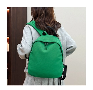 Rear view of model wearing a bright green Oxford fabric backpack with black straps