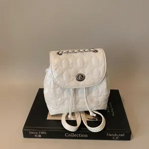 Detail of white mini backpack featuring star-quilted texture and silver twist lock closure